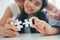 Happy family, Asian daughter playing jigsaw puzzle with her mother for family concept, Adult woman teaches child to solve puzzles