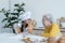 Happy family Asian elderly grandmother and little cute grandchild spend time together at kitchen, sift flour, knead dough and bake