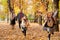 Happy family is in autumn city park. Children and parents running with leaves.. They posing, smiling, playing and having fun.