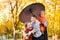 Happy family is in autumn city park. Peoples are posing under umbrella. Children and parents are smiling, playing and having fun.