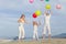 Happy family with balloons playing on the beach at the day time.
