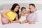 Happy family on bed in bedroom married couple with small child and pregnant woman - baby feeds father