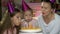 Happy family birthday party at home. Close up of mother with children blowing candles on birthday cake in slow motion