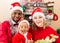 Happy family: black father, mom and baby boy dressed costume Santa Claus by fireplace