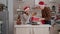 Happy family bringing wrapper christmas present gift with ribbon on it in xmas decorated kitchen