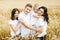 Happy family - brothers, sister and mom have fun on the wheat field. Summer vacation time