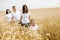 Happy family - brothers, sister and mom have fun on the wheat field. Summer vacation time