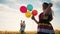 happy family celebrates birthday in the park. girl a holding colorful balloons silhouette in the field. dad throws