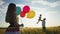 Happy family celebrates birthday in the park. Lifestyle girl a holding colorful balloons silhouette in the field. Dad