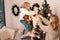 Happy family with child decorate christmas tree. Little girl sitting on daddy`s shoulders hangs ball on the Christmas tree.