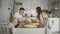 Happy family with children around kitchen table having breakfast