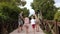 A happy family with children with bare feet running across the bridge.