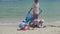 Happy family with children and dog playing on the sandy beach with toys. Tropical island, on a hot day