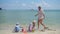 Happy family with children and dog playing on the sandy beach with toys. Tropical island, on a hot day
