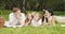 Happy family with children lying on the grass looking at each other and smiling during a picnic in a picturesque green garden