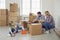 Happy family with children moving with boxes in a new apartment house.