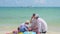 Happy family with children playing on the sandy beach with toys. Tropical island, on a hot day