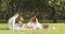 Happy family with children resting on the grass during a picnic in the picturesque green garden. Outdoors