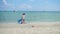 Happy family with children walking on the sandy beach. Tropical island, on a hot day