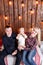 Happy family at Christmas. The parents and the baby sitting. Wall of wooden planks and garland