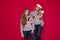 Happy family in Christmas sweater posing on a red background in the studio. Enjoying love hugs, holidays people. Mom and doughter