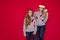 Happy family in Christmas sweater posing on a red background in the studio. Enjoying love hugs, holidays people. Mom and doughter