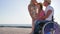 Happy family communicates on background blue sky and sea coast, disabled with pregnant wife and daughter hugging