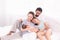 Happy family concept, father and daughter sit on bed excited looking new member in family, adorable newborn sleep on mother chest