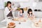 Happy family cooking together mom reading a book and two dauther preparing a bake