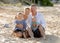 Happy family couple sitting on beach sand with baby boy son and daughter