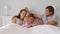 Happy family with cute little kids son daughter tickling having fun relax on bad together, young carefree parents and