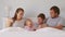Happy family with cute little kids son daughter tickling having fun relax on bad together, young carefree parents and