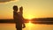 Happy family dad and baby, daughter hugging on the lake at sunset. Father and child child in the sun. Childhood dream