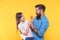 Happy family dad and daughter eat lollipop yellow background, share with me concept