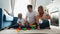 Happy family dad mom and baby 2 years playing lego in their bright living room. Slow-motion shooting happy family