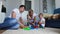 Happy family dad mom and baby 2 years playing lego in their bright living room. Slow-motion shooting happy family