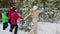 Happy family dancing around fir tree in winter forest