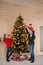 Happy family decorate the Christmas tree indoors together. Loving family. Merry Christmas and Happy Holidays