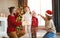 Happy family decorate Christmas tree, parents play with children with garlands