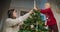 Happy family decorating Christmas tree installing topper star together