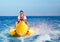 Happy family, delighted father and son having fun, riding on banana boat during summer vacation