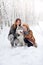 The happy family with dogs huskies poses in beautiful for the snow wood. Trees in snow