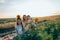 Happy family enjoying picnic together, sitting at the plaid among the mealow, beautiful teen girl with sunflower on her