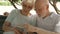 Happy family enjoying vacation in Europe. Seniors sitting on bench in park browsing in smartphone