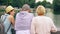 Happy family enjoying vacation. Seniors and their teenage daughter stand by lake in park sightseeing