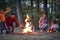 A happy family excited because of a campfire in the forest