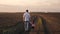 A happy family, a farmer father and a little daughter are walking in plowed field. The kid holds dad`s hand. Baby and
