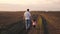 A happy family, a farmer father and a little daughter are walking in plowed field. The kid holds dad's hand. Baby and