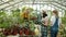 Happy family of farmers adults and child talking writing in notebook checking pot plants in orchard