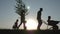 Happy family of farmers with tools at sunset. Silhouette. The family plants a tree in the fresh air. The way of life in